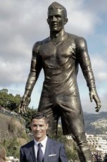 Portuguese football player Cristiano Ronaldo from Real Madrid poses beneath a statue of himself during the unveling ceremony in his hometown in Madeira.